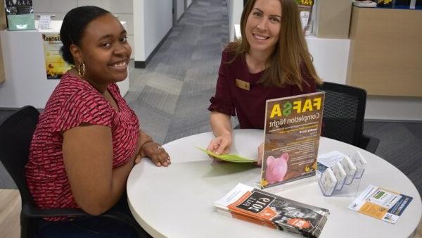 Financial Aid director and student sitting at a table smiling